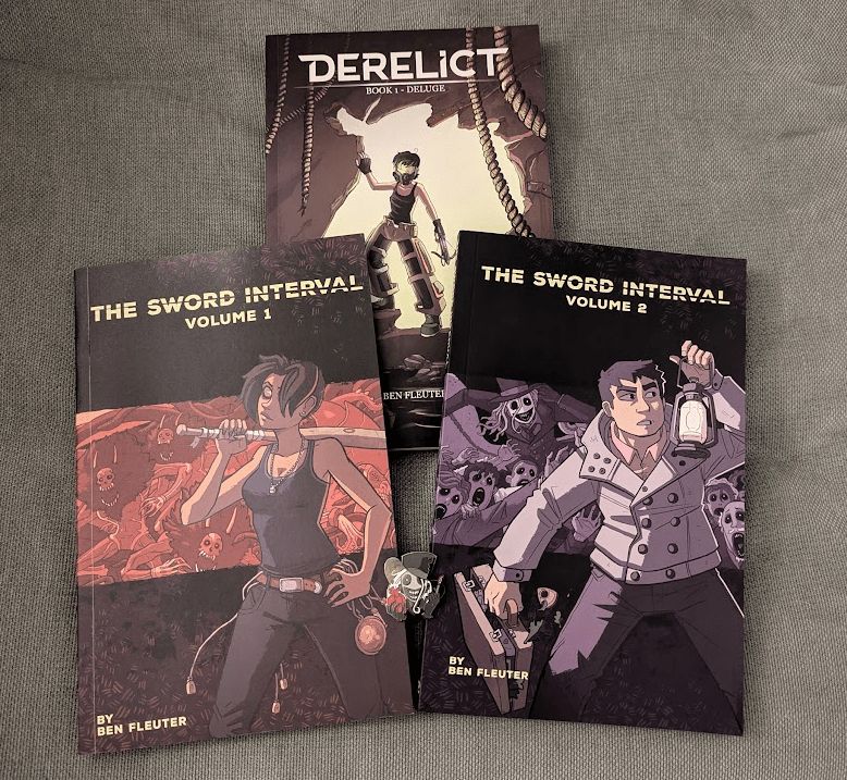 Printed paperback volumes 1 and 2 of the webcomic "The Sword Interval", and a copy of Ben Fleuter's other printed comic "Derelict" for good measure, photographed on the reviewer's sofa.